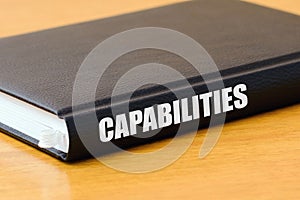 Book with CAPABILITIES inscription lie on the wooden table