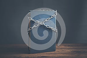 Book chained with lock on wooden table