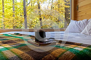 Book and coffee on a cozy bed in a rustic cabin