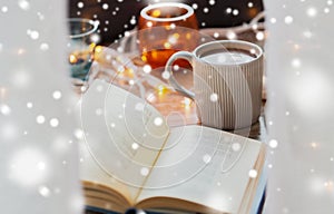 Book and cup of coffee or hot chocolate over snow