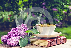 Book, cup of tea and lilac. Fragrant tea in the garden. Romantic concept.