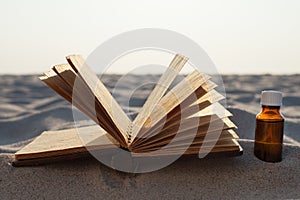 Book and Essential Oil on Sandy Beach