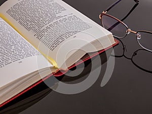 Book and glasses on the glass table with reflection of subjects