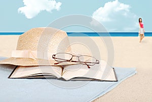 Book glasses and hat on the beach