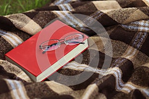 Book and glasses on the plaid, reading