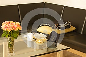 Book, glasses, roses, knitware and a mug with tea on modern glass table. Living room interior home decor concept