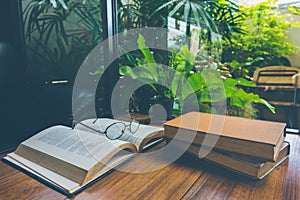 Book with glasses on table, vintage picture style.