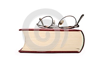 Reading glasses on top of an old book. White background