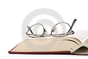 Reading glasses on top of an old book. White background