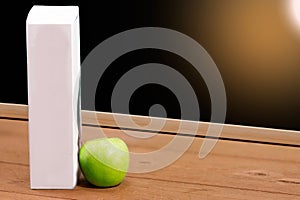 Book and Green apple on chalkboard background.