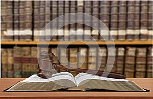 Book with judge hammer on bookshelves background