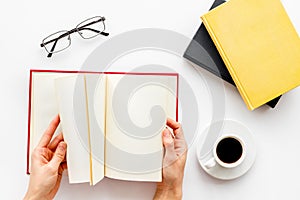 Book in hands for reading and education with coffee and glasses on white background flatlay