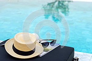 Book and hat on the sun bed near the swimming pool