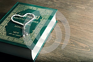 The book of the Koran with white beads on a wooden table photo