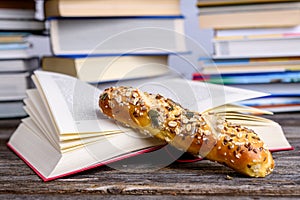 Book and little whole grain bread in front of piles of different books