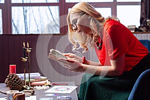 Blonde-haired female diviner feeling busy while reading book for magicians