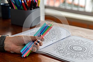 book of mandalas for coloring and a hand with crayons