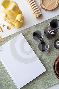 Book mockup design. Blank white book on dining table in asian style with tableware