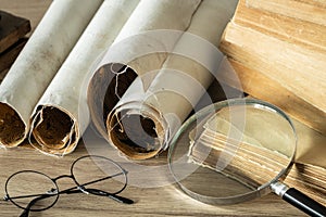 A book with old-fashioned glasses, a magnifying glass and rolled up old parchments