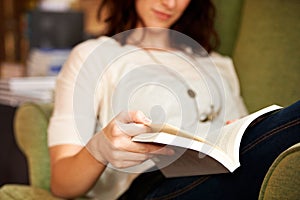 This book is a page turner. A cropped shot of a young woman reading a book while seated.