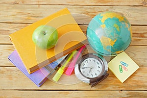 Book pile with apple, globe, pencils and sharpener on the school blackboard. Teacher`s day concept