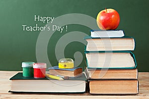 Book pile with apple, globe, pencils and sharpener on the school blackboard. Teacher`s day concept