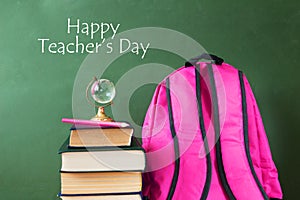 Book pile with apple, globe, pencils and sharpener on the school blackboard. Teacher`s day concept