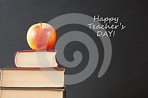 Book pile with apple, globe, pencils and sharpener on the school blackboard. Teacher`s day concept