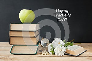 Book pile with apple, globe, pencils and sharpener on the school blackboard. Teacher`s day concept