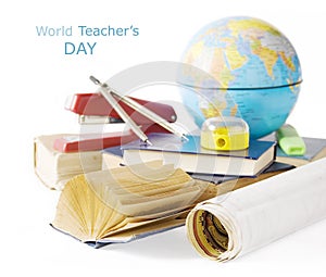 Book pile with apple, globe, pencils and sharpener on the school blackboard. Teacher`s day concept
