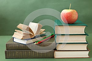 Book pile with apple, globe, pencils and sharpener on the school blackboard. Teacher`s day concept