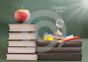 Book pile with apple, globe, pencils and sharpener on the school blackboard. Teacher`s day concept