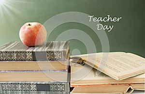 Book pile with apple, globe, pencils and sharpener on the school blackboard. Teacher`s day concept