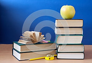 Book pile with apple, globe, pencils and sharpener on the school blackboard. Teacher\`s day concept