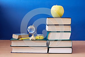 Book pile with apple, globe, pencils and sharpener on the school blackboard. Teacher`s day concept