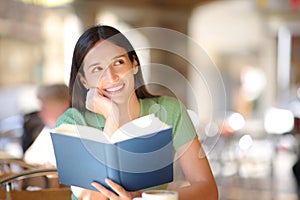 Book reader dreaming in a coffee shop terrace