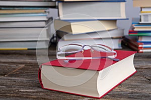 Book and reading glasses in front of piles of different books