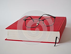 Book and reading glasses on a white background
