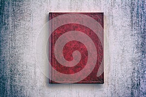 The book in a red cover over gray grunge background, top view