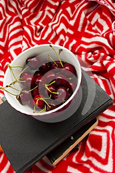 The book and red ripe cherries. Two ripe cherries look out of the book. Cherries as an unusual bookmark for the book