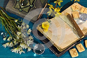 Book of spells, open diary and runes with flowers on ritual altar table. Occult, esoteric and divination still life. Mystic