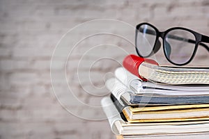 Book stack and glasses set in room with vintage brick background, education book reading concept