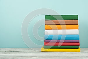 Book stack, hardback colorful books on wooden table and blue background. Back to school. Copy space for text. Education