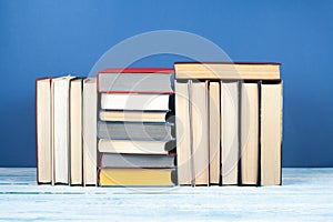 Book stack, hardback colorful books on wooden table and blue background. Back to school. Copy space for text. Education