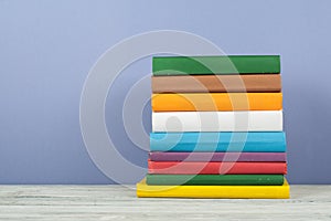Book stack, hardback colorful books on wooden table and blue background. Back to school. Copy space for text. Education concept