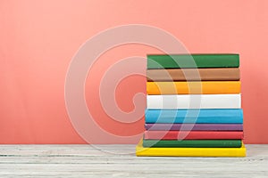 Book stack, hardback colorful books on wooden table and blue background. Back to school. Copy space for text. Education concept