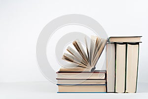 Book stack, hardback colorful books on wooden table, white background. Back to school. Copy space for text. Education