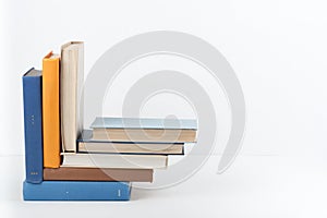 Book stack, hardback colorful books on wooden table, white background. Back to school. Copy space for text. Education