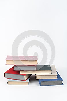 Book stack, hardback colorful books on wooden table, white background. Back to school. Copy space for text. Education