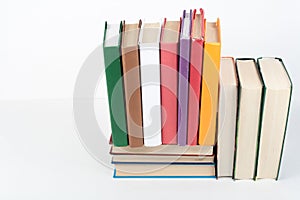 Book stack, hardback colorful books on wooden table, white background. Back to school. Copy space for text. Education